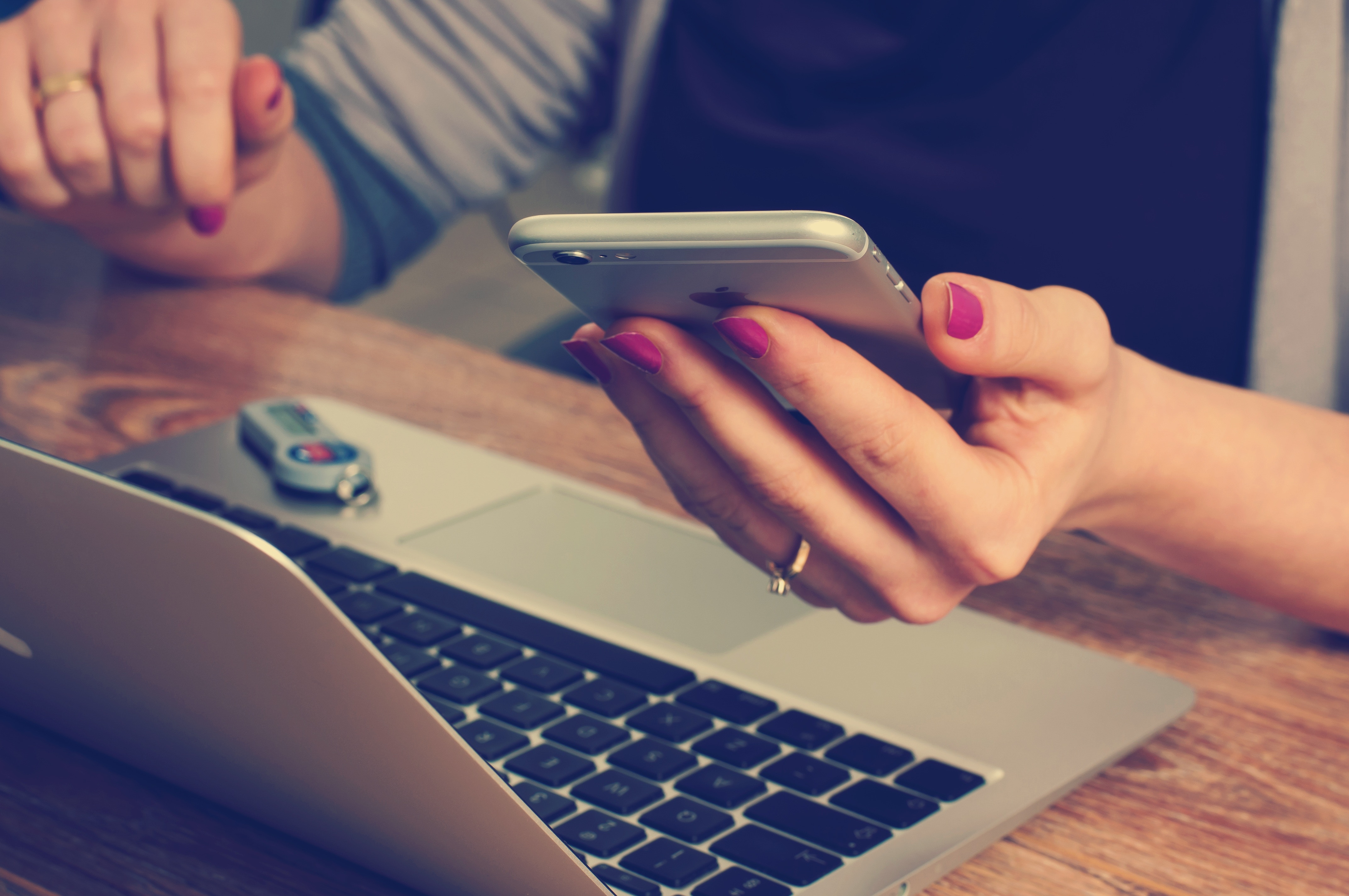 Person on laptop checking phone